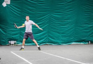 Ashley Heather hitting a forehand return on a tennis court.